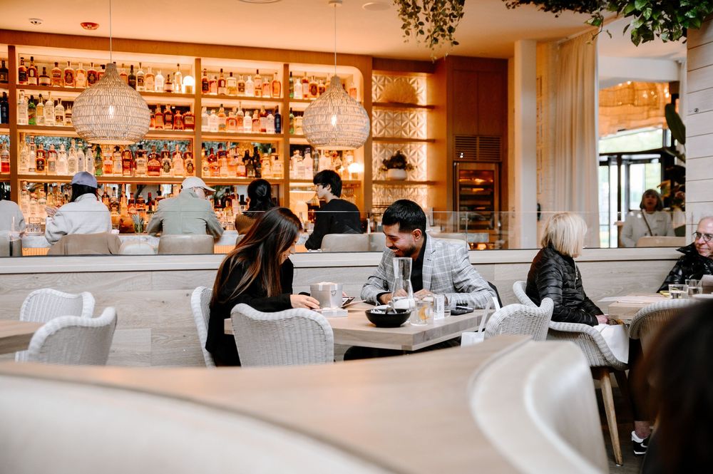 Modern restaurant interior with well-stocked bar and curved seating areas illuminated by warm lighting.