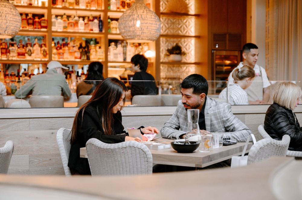 Warm-toned restaurant interior with patrons dining at tables under soft lighting.