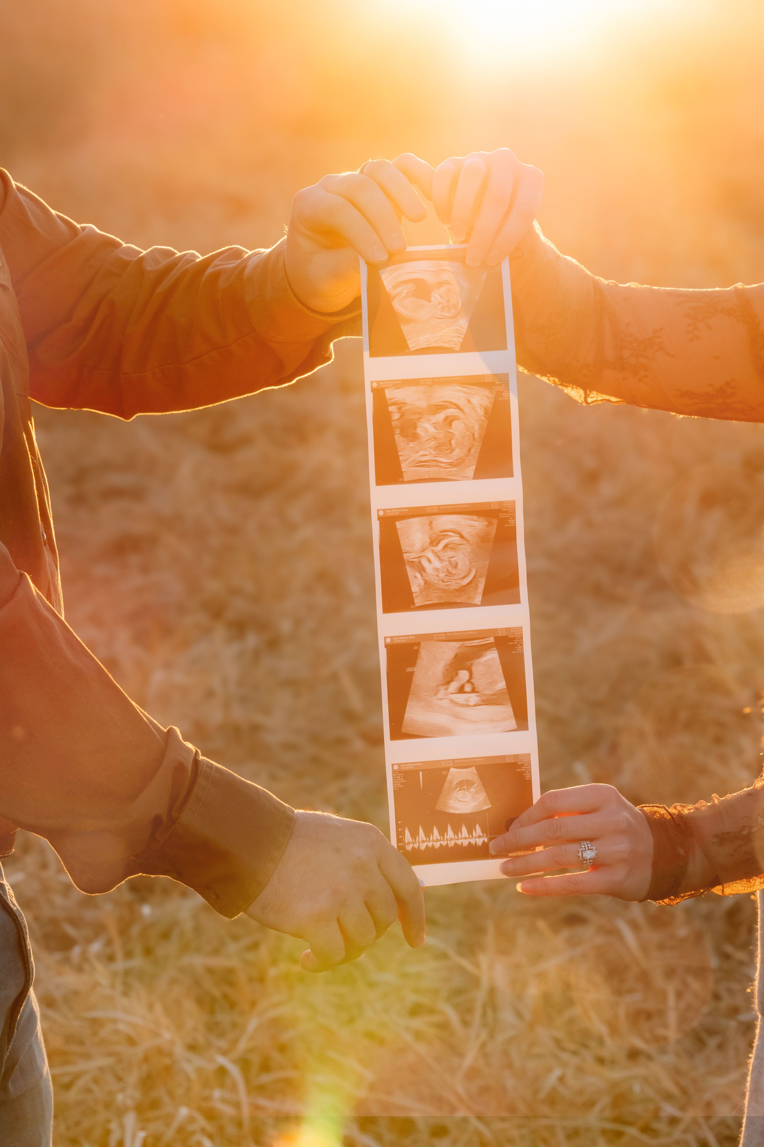 Hands holding instant photos against a warm sunset background with golden light filtering through.