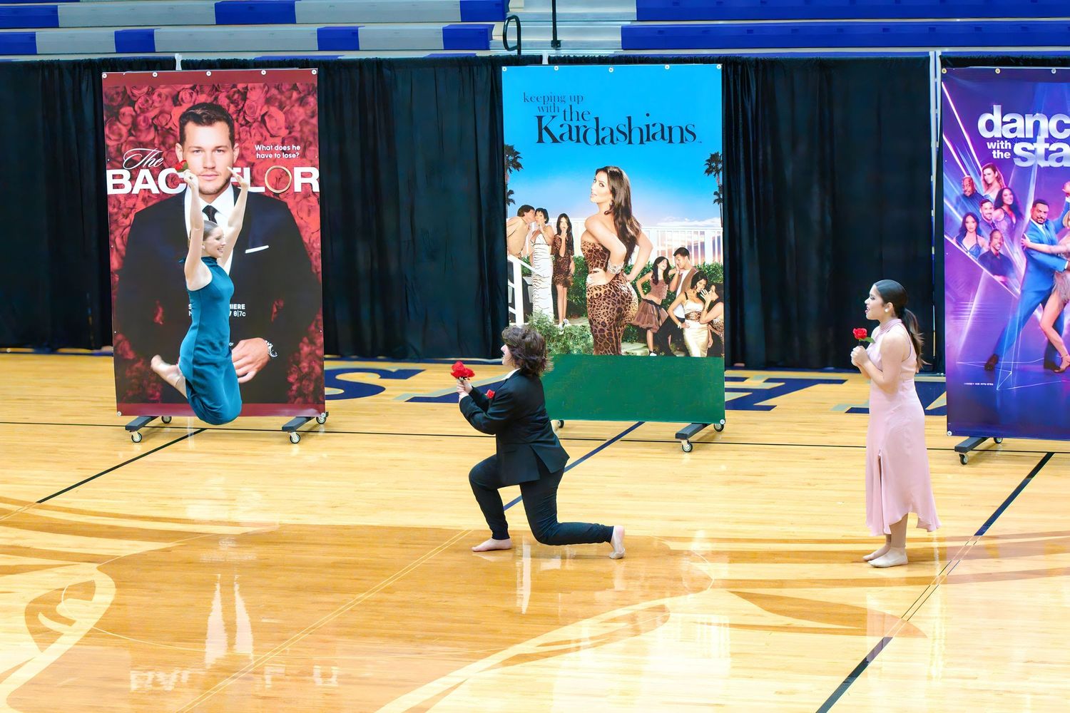 Children perform choreographed dance moves on a gymnasium floor during a dance competition or recital.