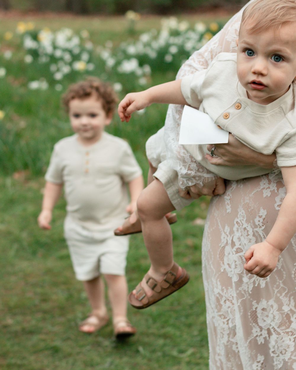A collection of candid photographs showing playful moments outdoors in a grassy field with white flowers.