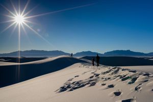 A sunburst over White Sands National Park in New Mexico creates a stunning silhouette against pristine gypsum dunes.