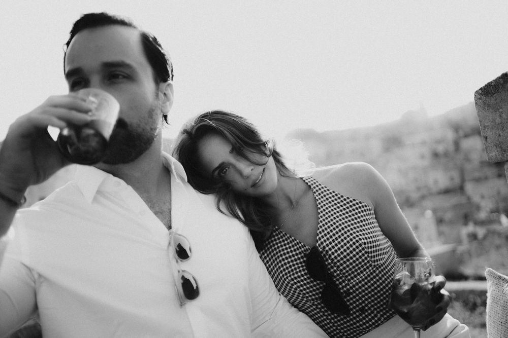 Black and white photo showing a couple enjoying drinks together on a sunny outdoor patio.