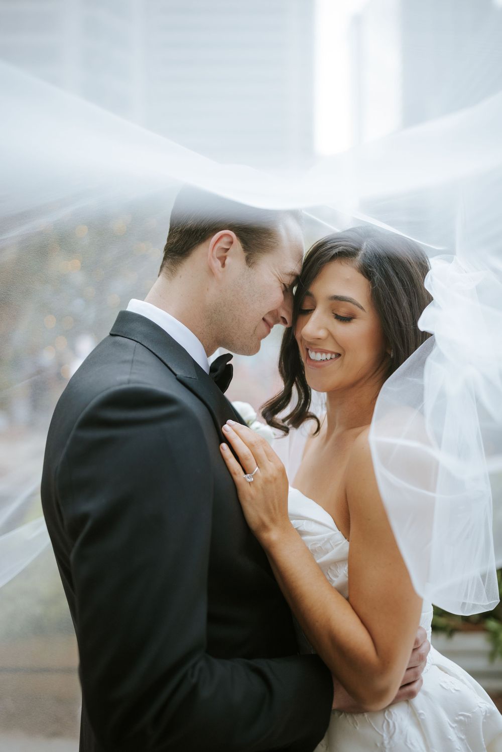 Bride and groom share a tender moment under the veil outside the Ritz-Carlton Philadelphia — romantic city wedding elegance.