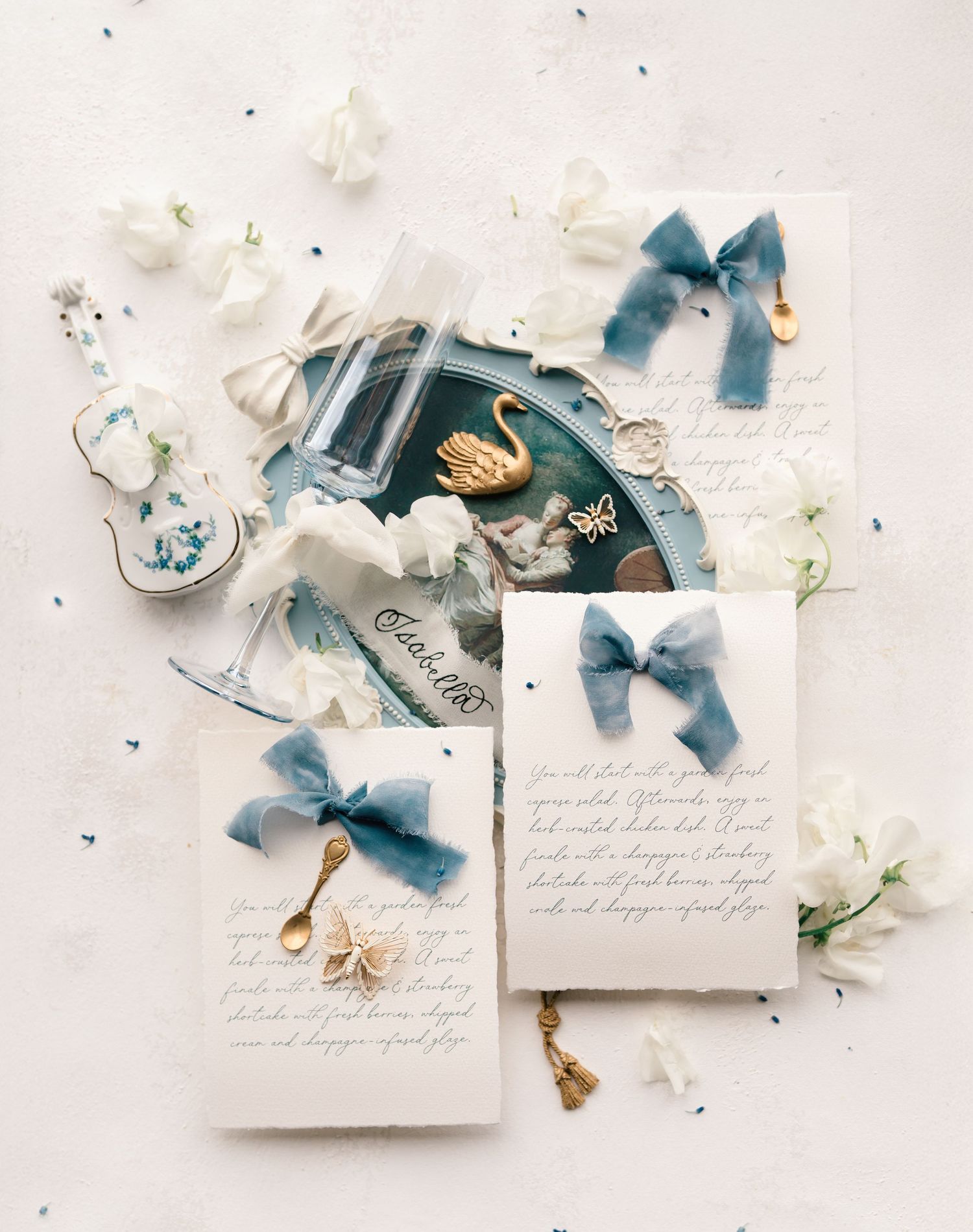 A series of elegant wedding invitations with delicate blue ribbons and white flowers arranged on a light background.
