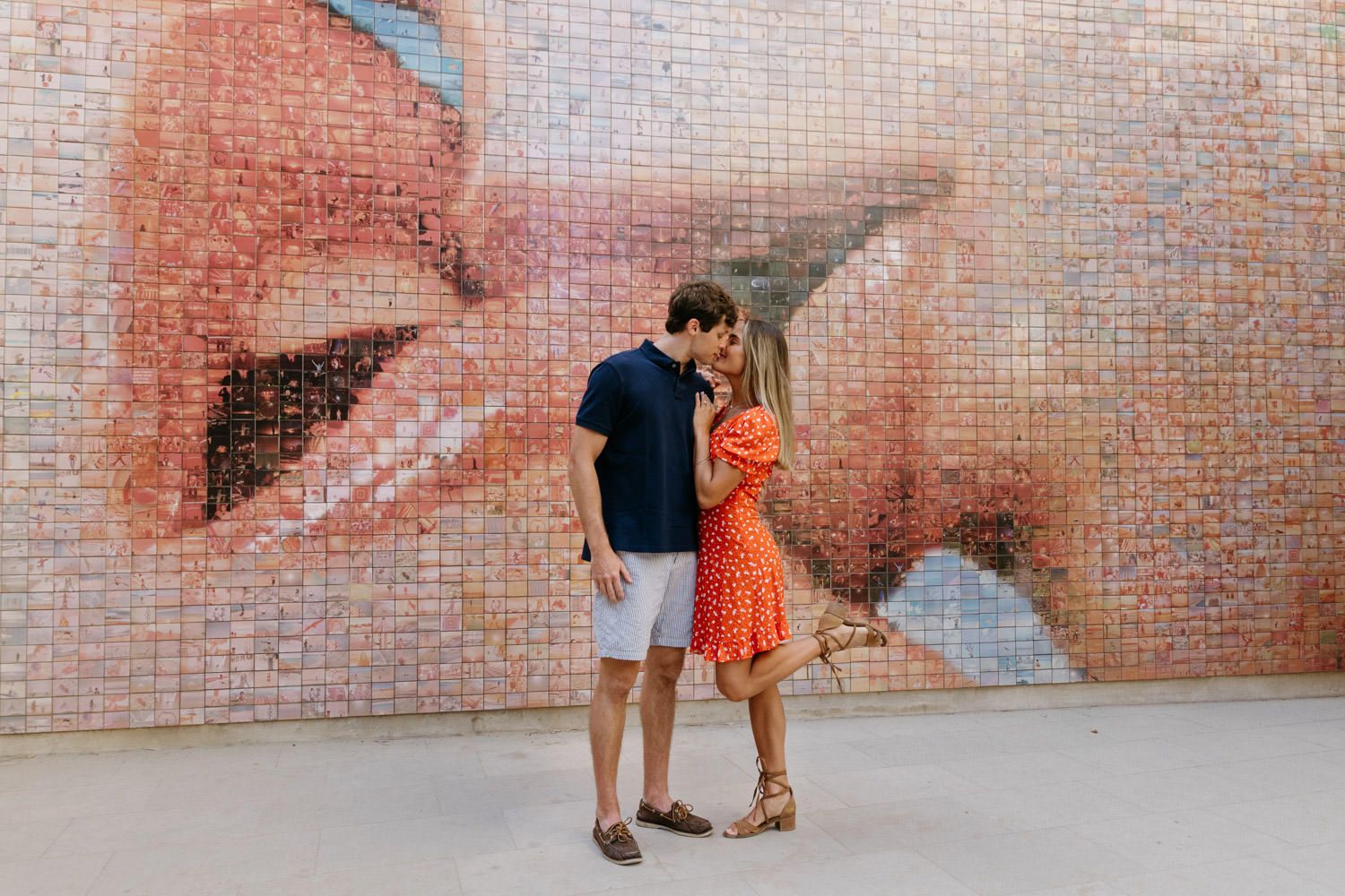 Couple sharing tender moments against a pink textured wall.