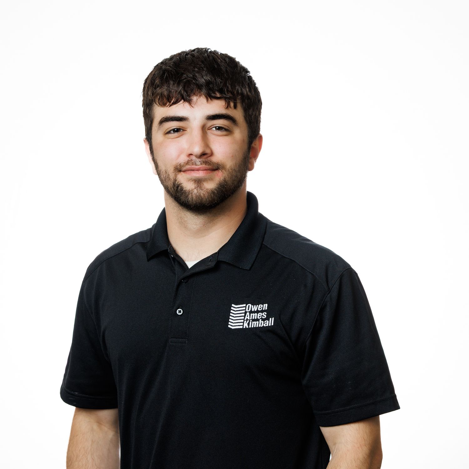 Professional portrait of staff members wearing black polo shirts against light background.