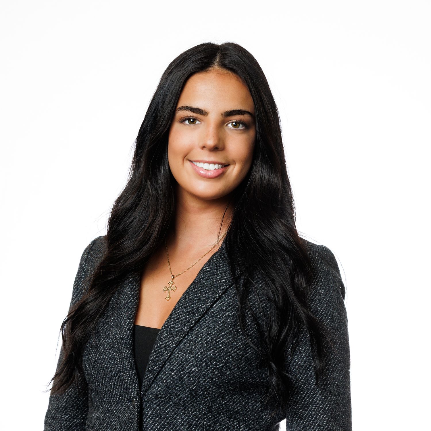Professional headshot of person with long dark hair wearing a dark textured blazer against white background.