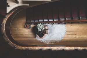 Aerial view looking down a curved wooden staircase with a white dress spread across the steps.
