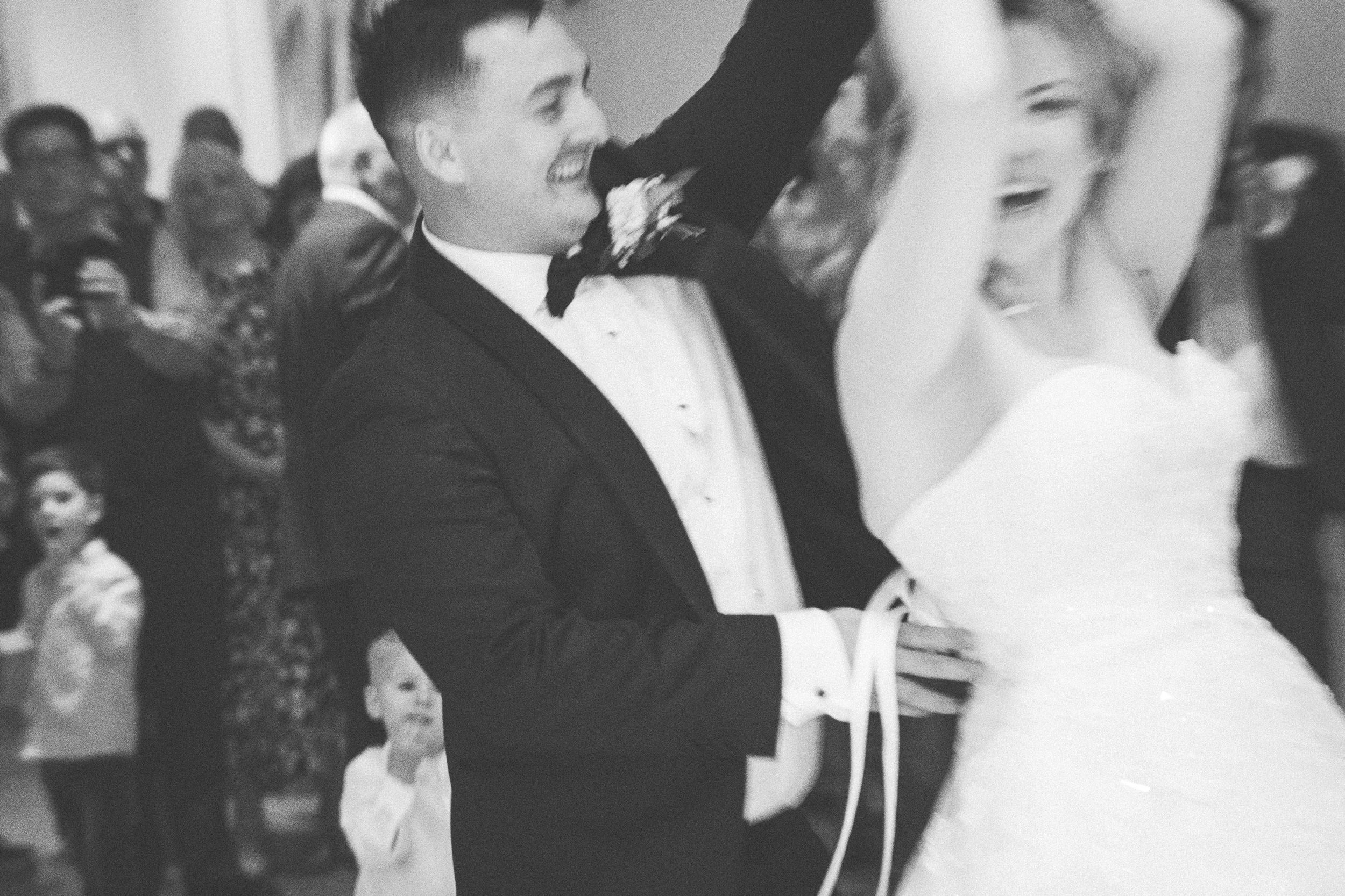 Joyful wedding couple shares their first dance together surrounded by guests at an elegant reception celebration.