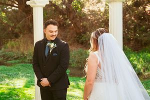 Newlywed couple shares romantic moments in a lush garden setting during an outdoor wedding ceremony.