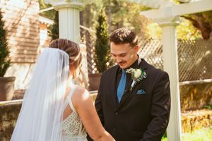 Intimate wedding moment captured outdoors with sunlight filtering through white garden pergola structures.