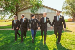 Wedding party members jump in unison wearing formal suits and dresses during outdoor photo session.