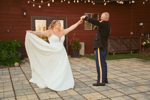 A couple shares a romantic dance moment on a patio with string lights overhead.