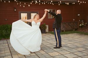 Couple dancing together on a brick patio beneath twinkling string lights.