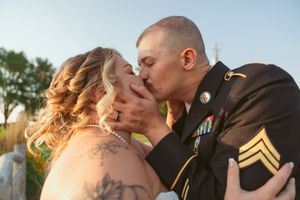 An intimate wedding portrait captured during golden hour showing visible tattoo art and military dress.