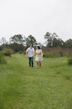 Couple walking together through a green meadow on overcast day.
