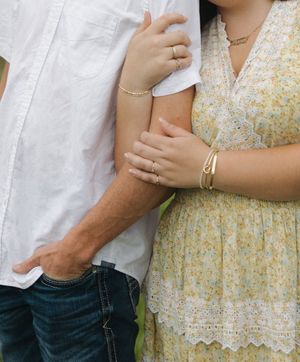Close-up of couple's embrace showing details of white shirt and floral dress.