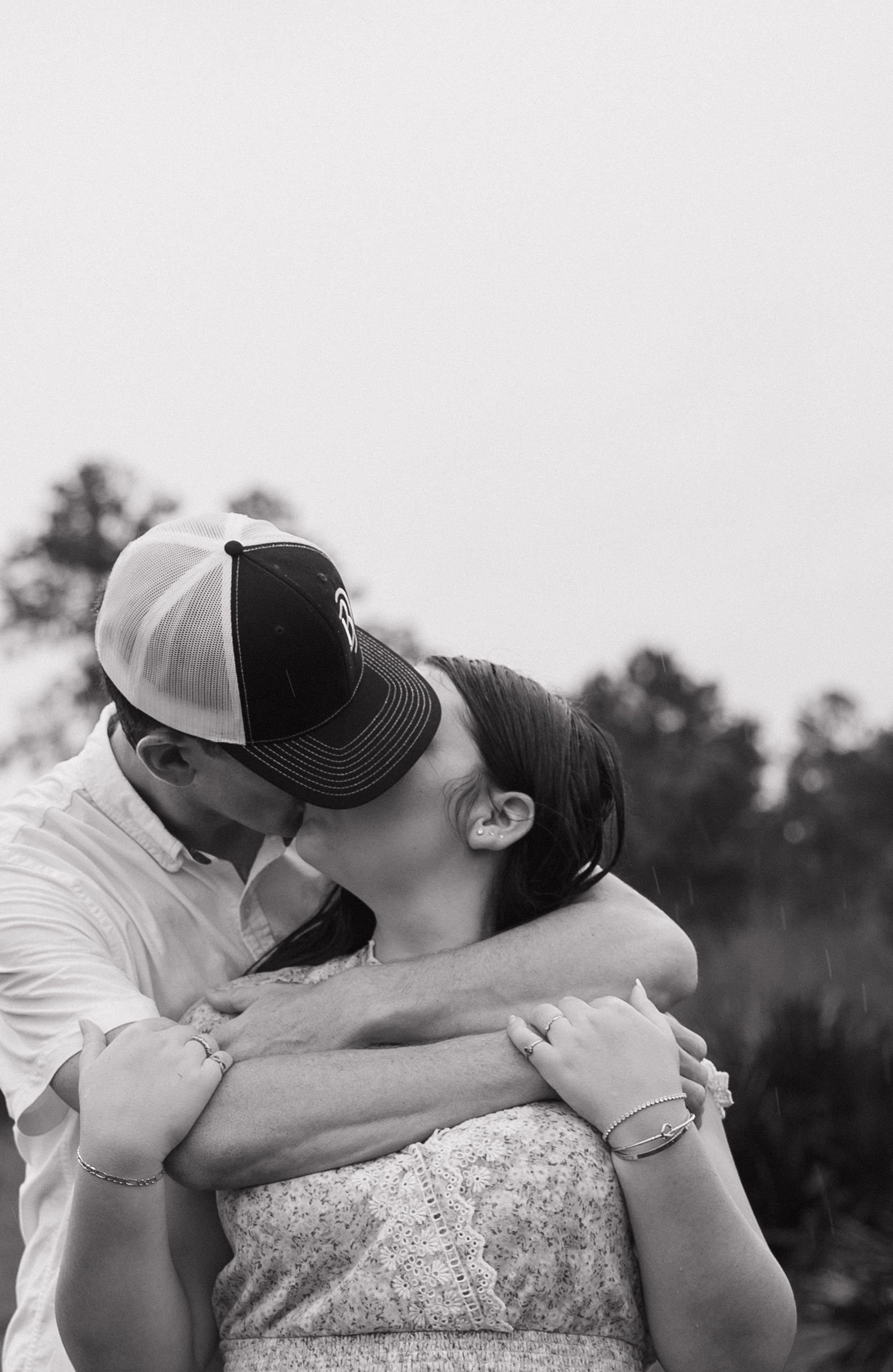 A tender black and white photo series of a couple embracing and kissing outdoors.