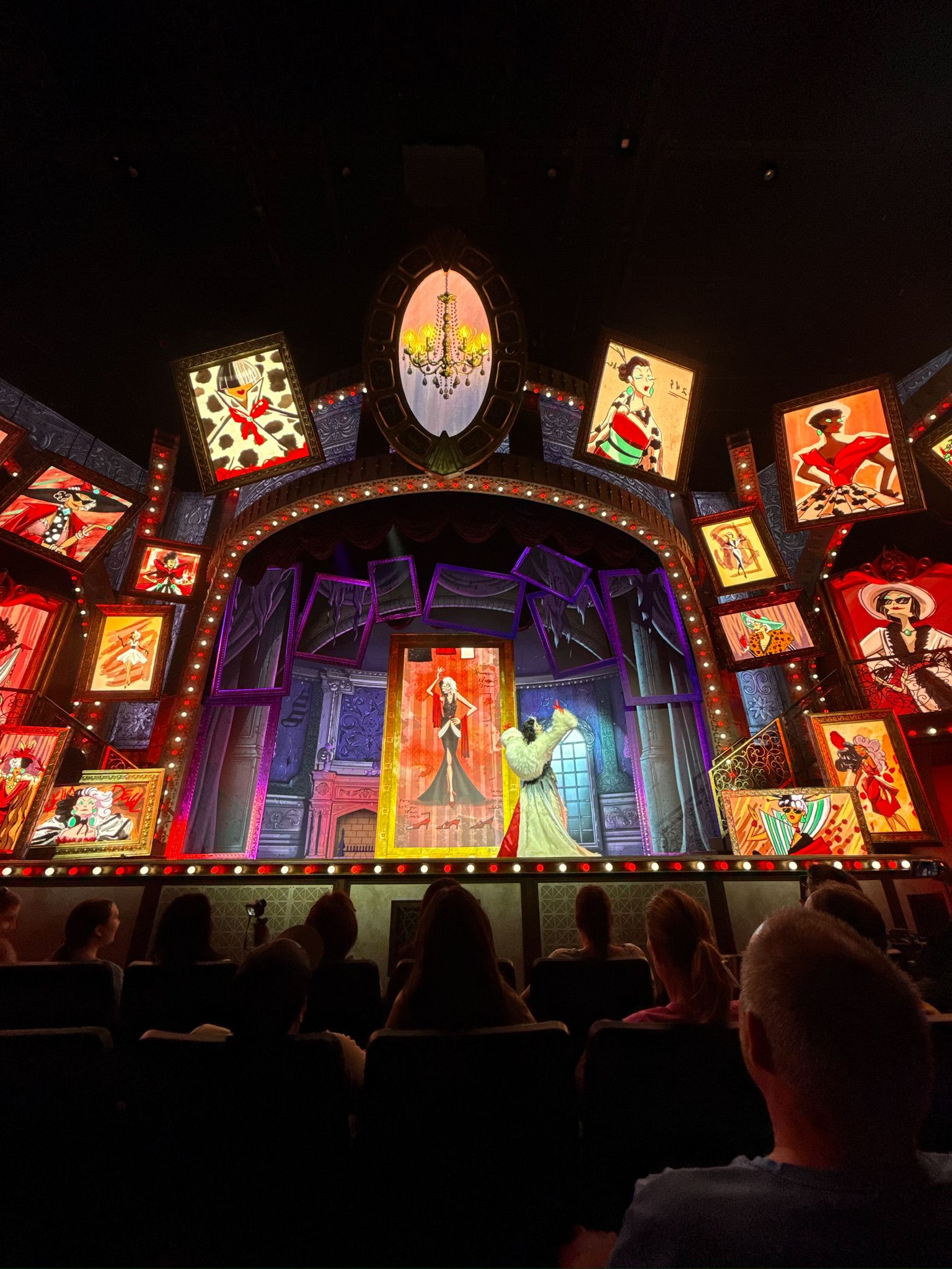 Illuminated theme park stage show with bright animated screens and decorative lighting elements.