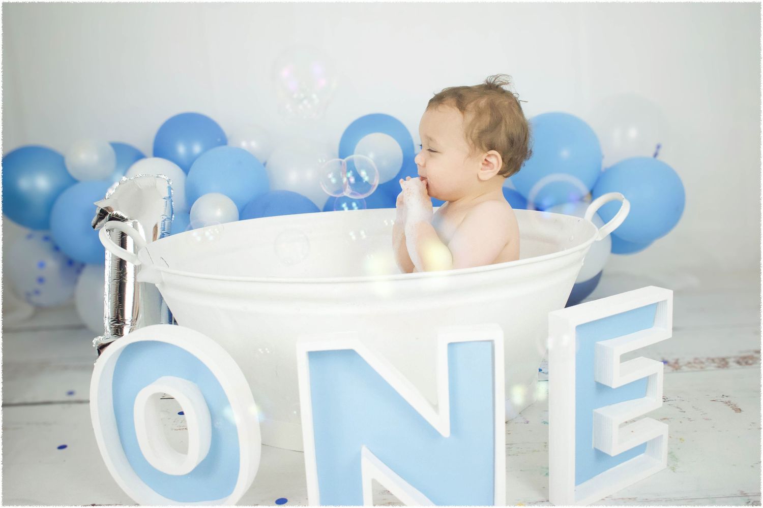 Blue and white balloon garland decorates birthday photo setup.