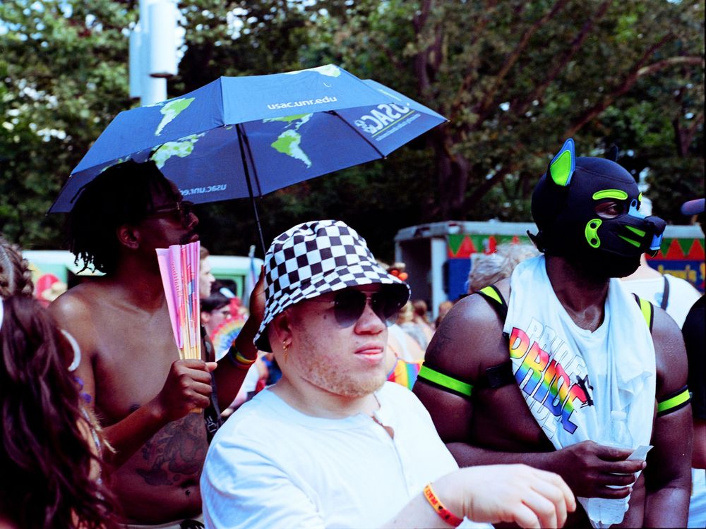 Festival attendees with umbrellas and colorful attire gathered at an outdoor music event.