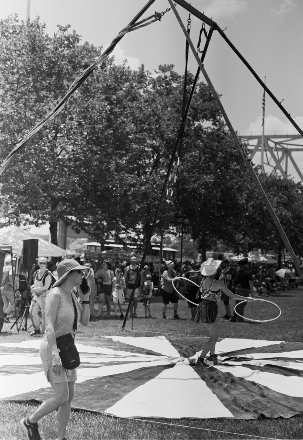 A series of black and white photographs showing someone performing aerial circus moves on a trapeze in an outdoor setting.