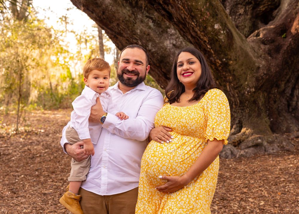 Family portrait under large oak tree at sunset.