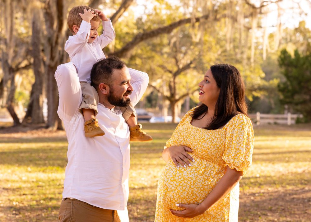A joyful outdoor maternity photo session in warm golden light at a park.
