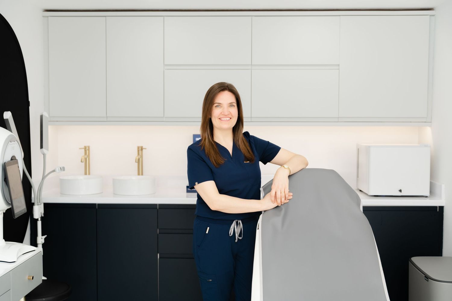 A tidy modern home office workspace with navy accents features a clean white desk against a gray wall.