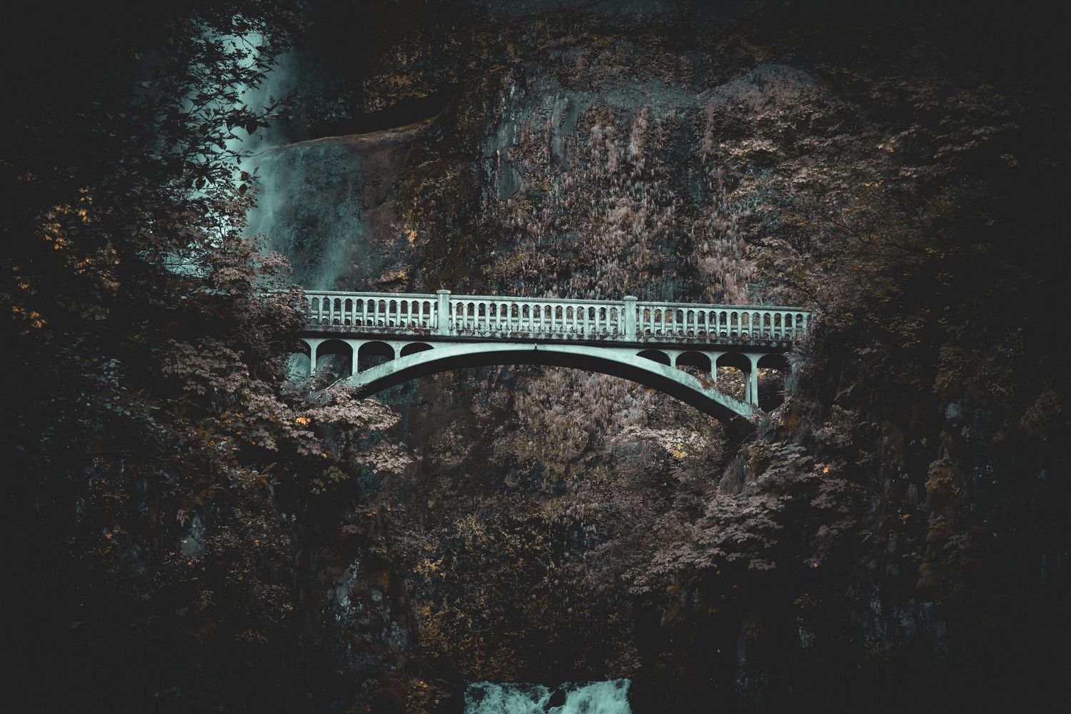 Dark moody landscape with a stone bridge in the distance.
