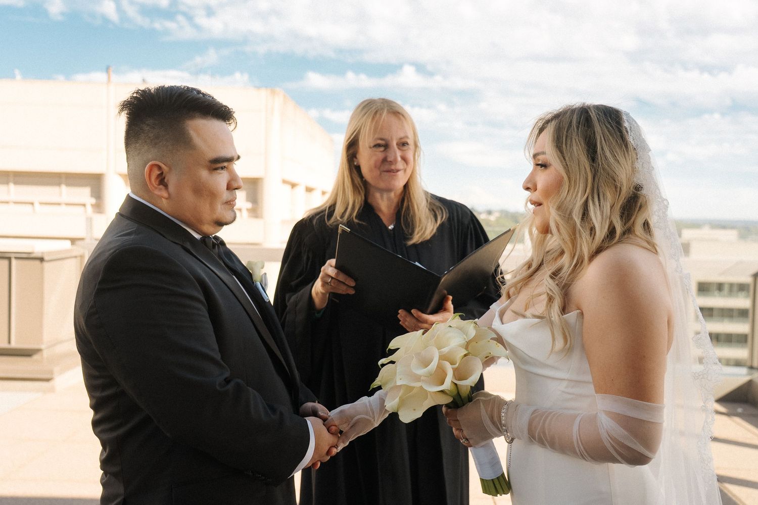 A couple exchanges vows during their rooftop wedding ceremony with an officiant presiding over the moment.