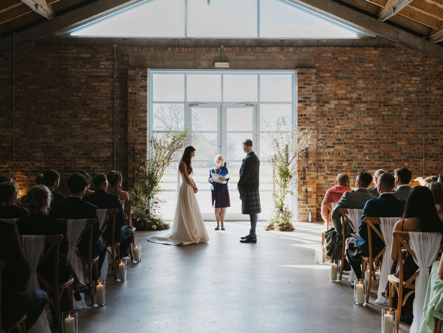 Close-up of bride in white dress standing next to person wearing traditional Scottish kilt.