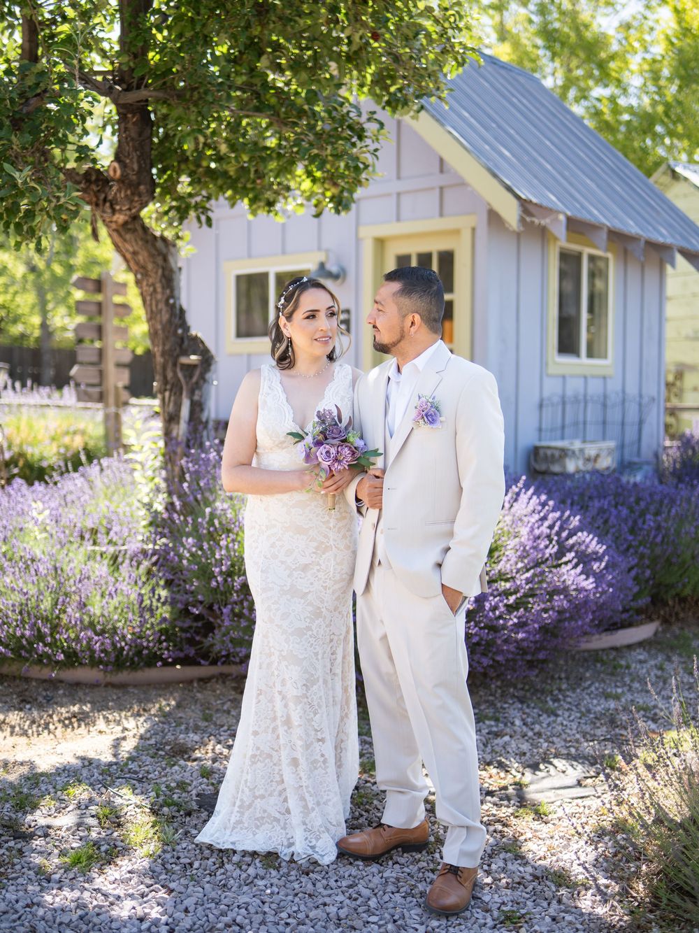 A charming lavender garden scene with a white cottage and couple in light wedding attire sharing a romantic moment.