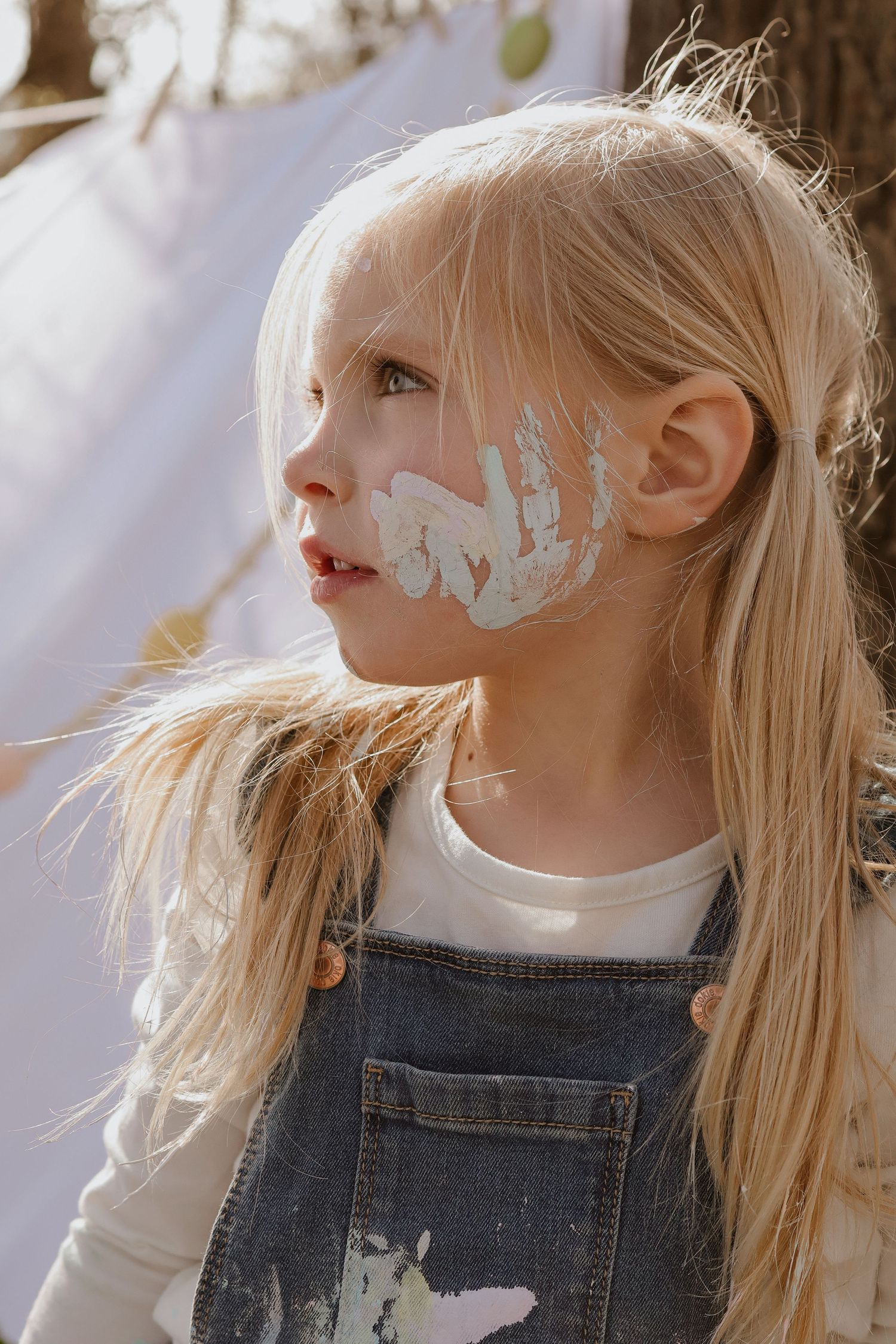 Profile view showing artistic face paint in soft pastel colors.