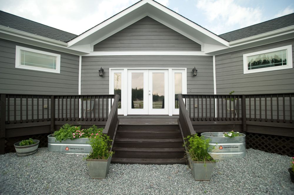 Modern gray house exterior with white french doors and wooden deck steps.