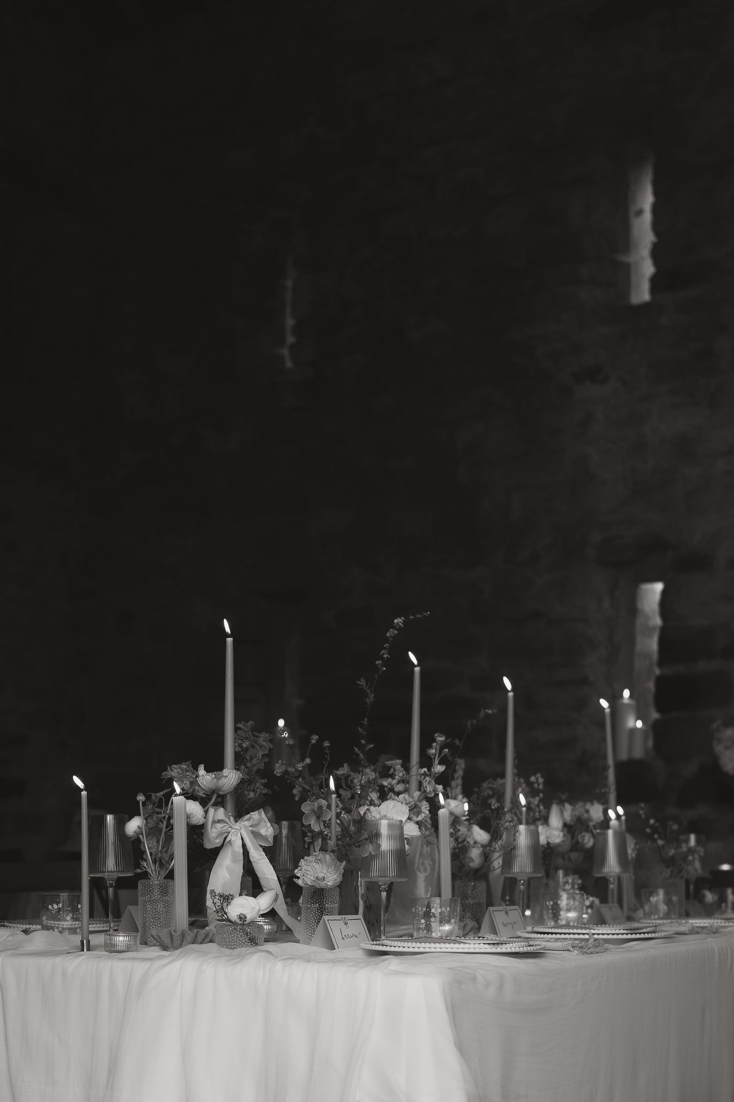 Elegant black and white table setting with tall white candles and floral arrangements on a crisp white tablecloth.