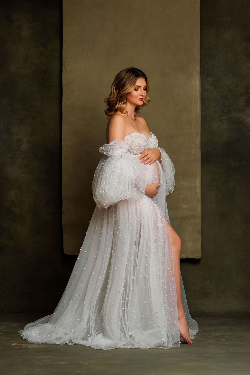 Side view maternity portrait in sparkling white off-shoulder gown with sheer details.