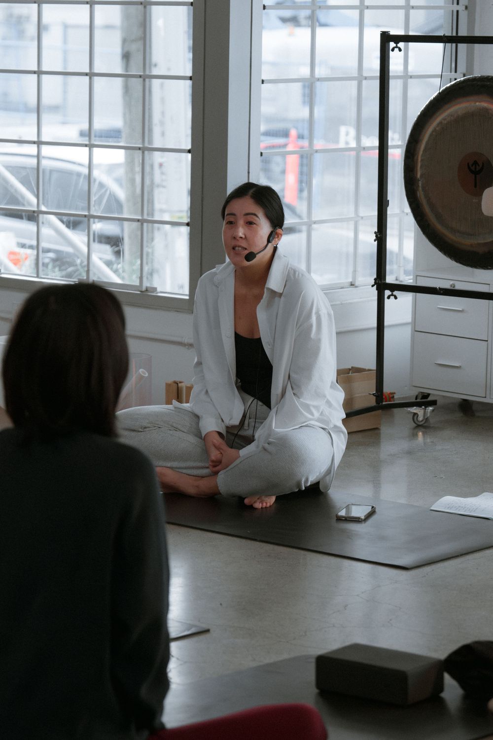 People practicing sound healing therapy with gongs in a bright, minimalist meditation studio space.