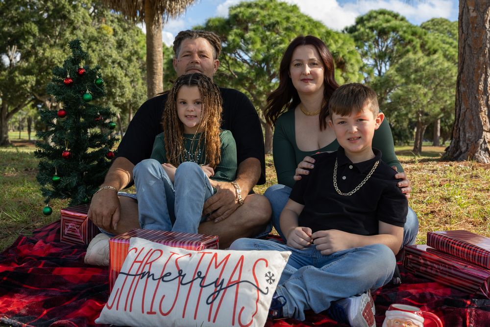 Holiday photo session with family members on red blanket outdoors.