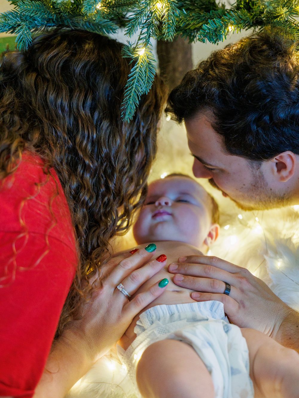 Couple sharing intimate holiday moment in front of Christmas tree with twinkling lights.