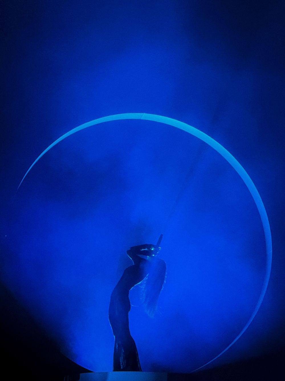 Silhouetted hand reaching up against a glowing blue circular light effect.