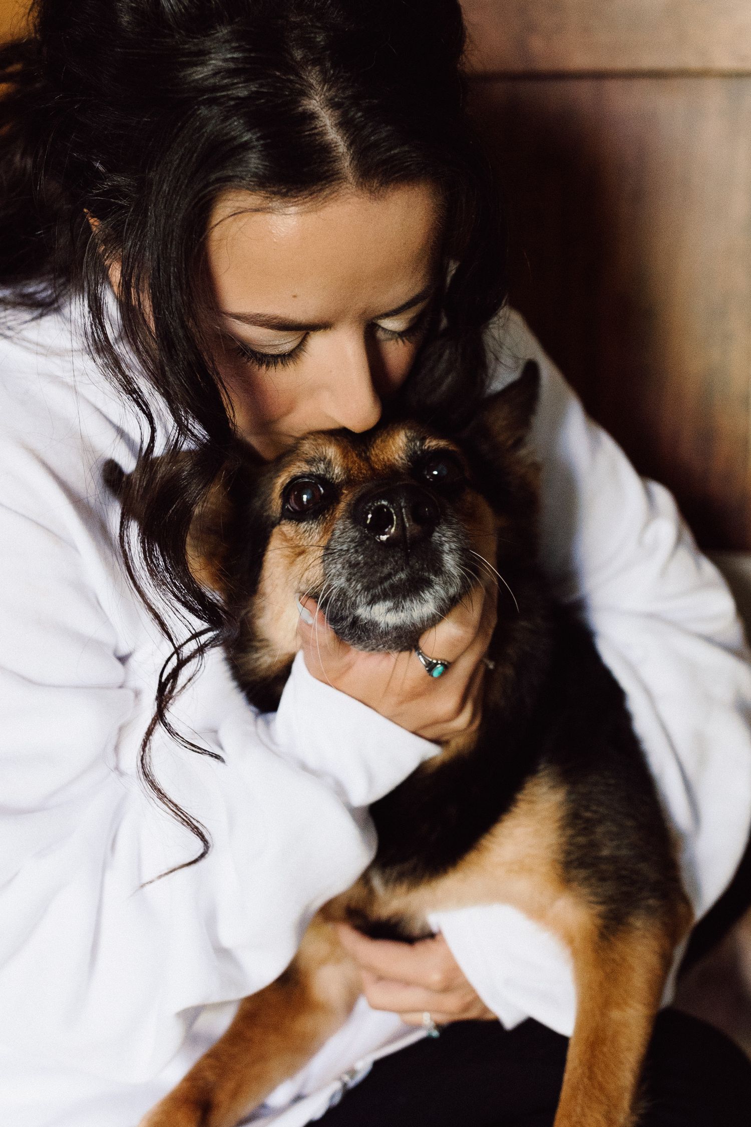 Close-up shots of someone in a white shirt lovingly cuddling with a small dog.