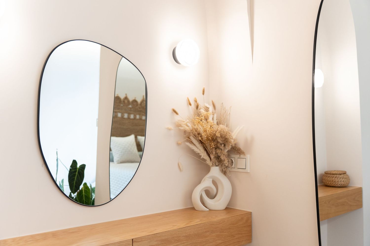 A collection of round mirrors and natural decor elements arranged on a white wall in a modern minimalist style.