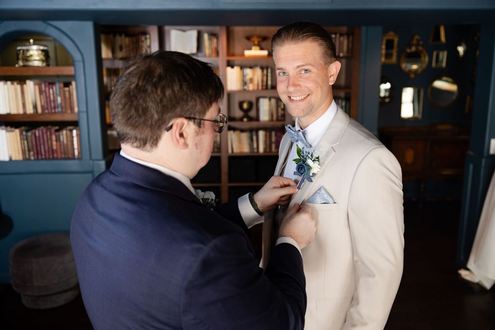 An elegant reception gathering with people in formal attire sharing drinks and conversations in a dimly lit room.