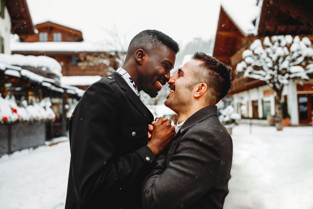 Couple shares intimate moments in a winter wonderland setting with snowy mountains and cozy cabins in background.