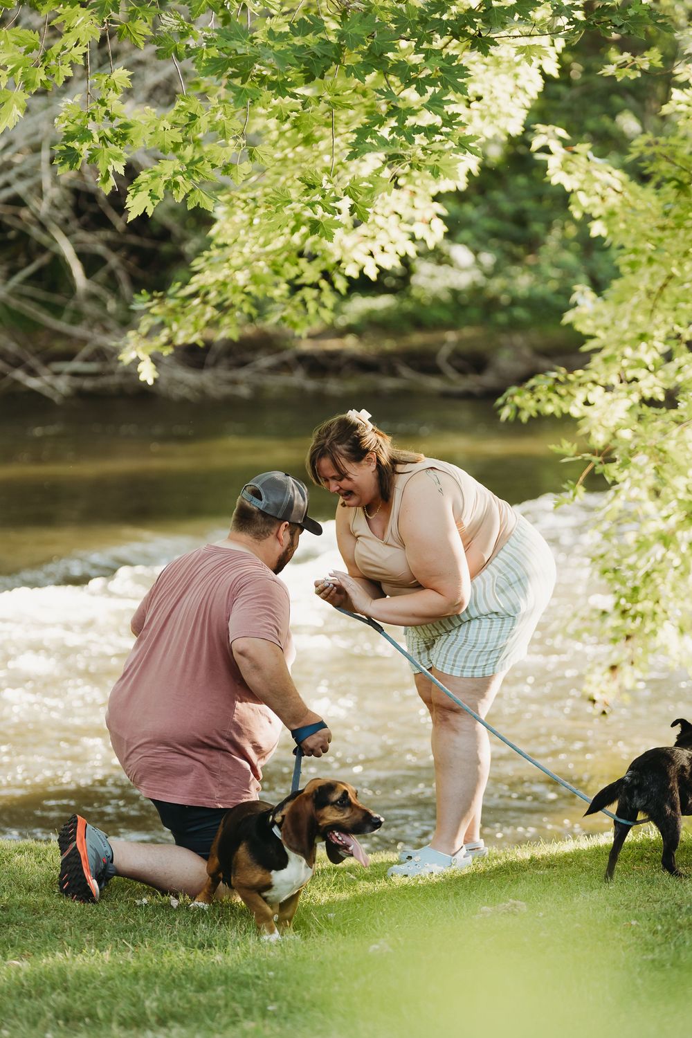 A cherished moment captured by a river as friends or family spend time with their dog in the summer shade.