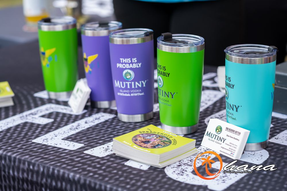 Colorful insulated drink tumblers in blue, purple, and green arranged on a dark surface with labels attached.