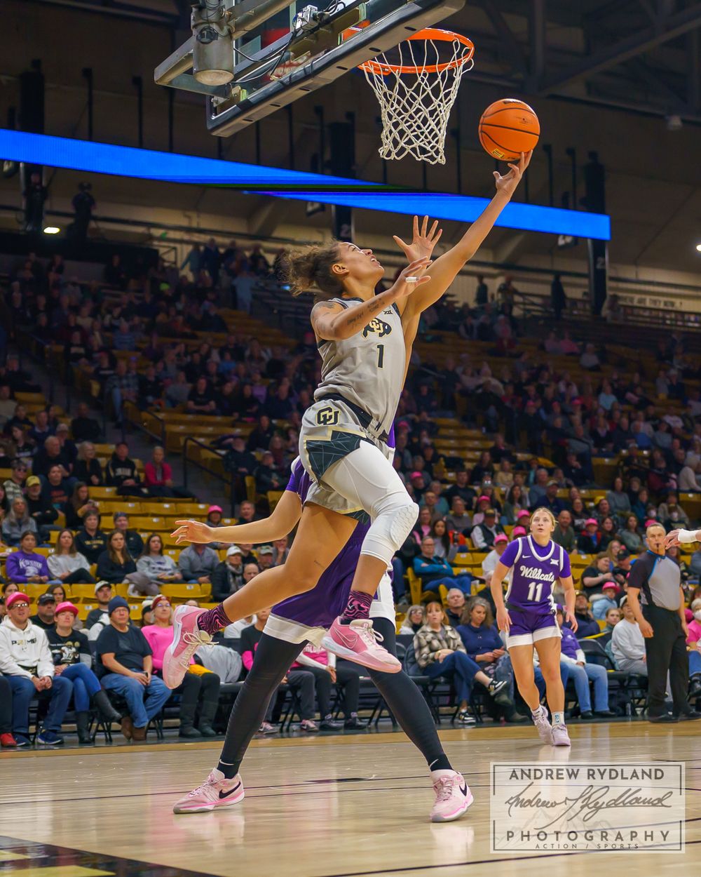 Basketball player drives to the hoop for layup during competitive game action.
