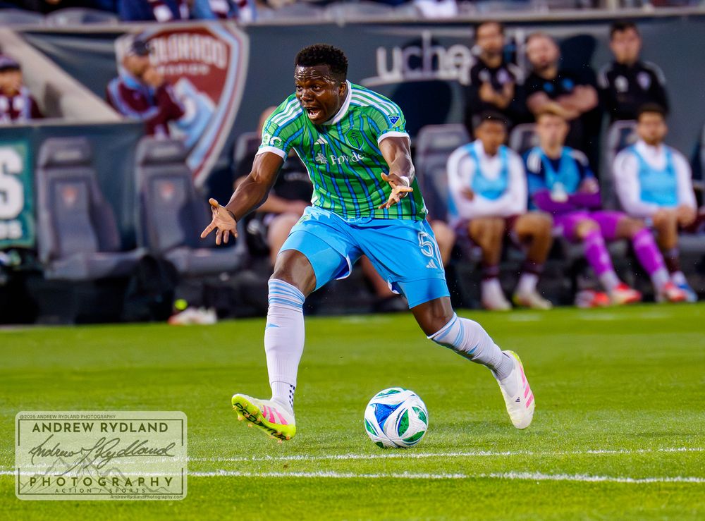 Soccer player in green jersey controls ball during professional match.